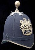 Two 1878 Pattern Blue Cloth Helmets. The first an officer’s with w/metal fittings, front peak trim and back spine...