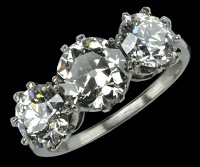 A three stone diamond ring, the three graduated brilliant-cut diamonds claw set to plain white precious metal mount,...