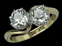 A two stone old-cut diamond crossover ring, the two old brilliant-cut diamonds in simple eight claw settings, in a...