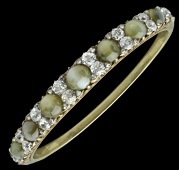 A late Victorian cat’s eye chrysoberyl and diamond hinged bangle, the seven graduated round cabochon cat’s eye...