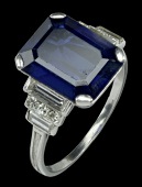 An Art Deco sapphire and diamond ring, the rectangular step-cut sapphire claw set between stepped shoulders set with...