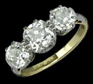 An early 20th century three stone diamond ring, claw set with central cushion-cut diamond and flanked each side by...