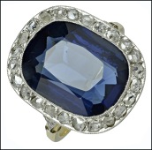 A diamond and blue glass dress ring, the oblong mixed-cut blue glass stone within a millegrained border of rose-cut...