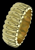 A large broad hinged bangle, of polished ribbed design, in yellow precious metal, stamped ‘CETAS, 750’ for 18ct...