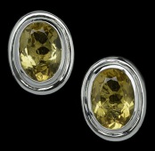 A pair of citrine earclips, the oval mixed-cut stones collet set in stepped plain polished mounts, in white precious...