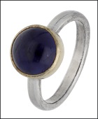 A silver iolite ring by Jane Mackintosh, 1997, the cabochon iolite within a silver gilt collet, to a silver band,...