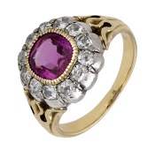 A late 19th century ruby and diamond cluster ring, the mixed-cut ruby bezel-set within a surround of old cushion-cut...