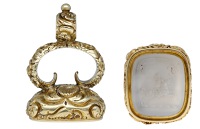 An early 19th century gold and hardstone seal, the cushion-shaped chalcedony intaglio carved with the crest of the...