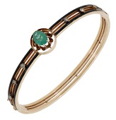 A gem-set bangle, circa 1900, the oval-cut green paste to an openwork knifewire bangle with black enamel detailing...