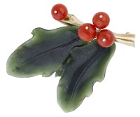 A hardstone brooch, realistically modelled as a holly sprig composed of Corallium rubrum drupes and nephrite leaves,...