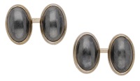 A pair of mid 20th century hematite cufflinks by Cartier, the oval hematite cabochons collet-set to closed back gold...