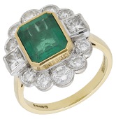 An emerald and diamond cluster ring, the step-cut emerald within a surround of brilliant and princess-cut diamonds,...