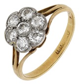 A diamond flowerhead cluster ring, set throughout with brilliant-cut diamonds, between trifurcated shoulders,...