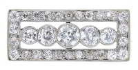 An Art Deco diamond panel brooch, set with a graduated row of old brilliant-cut diamonds, within a...