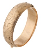 A bangle by Birks, the front with engraved foliate and scroll design, signed ‘BIRKS’, stamped ‘10K’, inner...