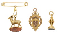 A group of two seals and a fob, comprising a springbok fob seal, inset with a hardstone seal base bearing Arabic...