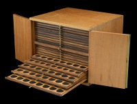 A mahogany coin cabinet by Swann, 33 x 31 x 25cm, comprising 20 trays double-pierced to house a total of 1,164 coins...