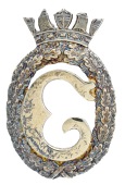 A silver-gilt Merchant Navy officer’s badge, the central initial within an oak leaf surround, beneath a naval...