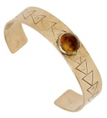 A 9ct gold and citrine bangle by Barbara Cartlidge, 1966, collet-set to the front with a sugarloaf citrine cabochon,...
