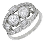 An Art Deco diamond dress ring, set with two old brilliant-cut diamonds, within an open surround of baguette and...