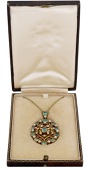 An early 20th century Arts and Crafts emerald pendant, the oval openwork drop with wirework heart and foliate...