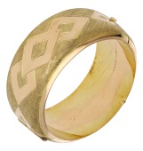 A broad bangle, with Florentine finish and polished lozenge decoration, stamped ‘18K’, inner diameter 5.8cm.	...