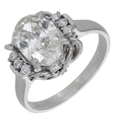 A diamond ring, the oval-cut diamond within a wirework gallery setting with brilliant-cut diamond highlights to each...
