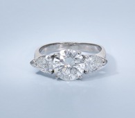 A diamond three stone ring, the central brilliant-cut diamond, weighing 2.08 carats, between two pear-shaped...