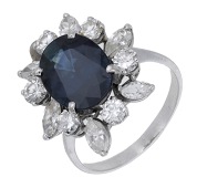 A sapphire and diamond cluster ring, the oval mixed-cut sapphire within a surround of brilliant and marquise-cut...