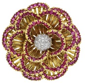 An 18ct gold, ruby and diamond brooch, circa 1963, of flowerhead design, the openwork petals tipped with...