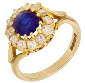 A sapphire and diamond cluster ring, 1980, the circular-cut sapphire within a surround of old brilliant-cut...