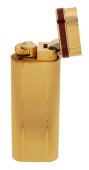 A gold plated lighter by Must de Cartier, of flattened cylindrical form, with engine-turned engraving and red enamel...