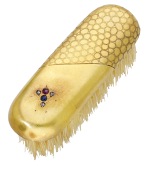 A gold mounted miniature clothes brush, probably Japanese, highlighted with rose-cut diamonds, a ruby and a...