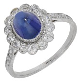 An early 20th century sapphire and diamond cluster ring, the sugarloaf sapphire cabochon within a surround of old...