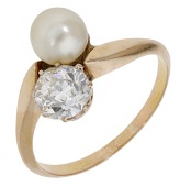 An early 20th century pearl and diamond ring, of crossover design, set with a bouton-shaped pearl, measuring...