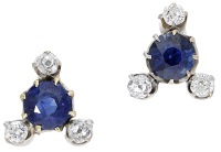 A pair of sapphire and diamond ear studs, of triangular design, each circular-cut sapphire within a trio of old...