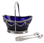 A Victorian silver sugar basket, the blue glass liner within an openwork frame hung with laureate swags, and having...