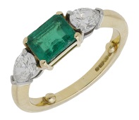 An emerald and diamond ring, the step-cut emerald between two pear-shaped diamonds, mounted in 18ct gold, UK...