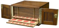 A wooden coin cabinet by Peter Nichols, 33 x 19 x 33cm, comprising 14 trays single-pierced to house various coins...
